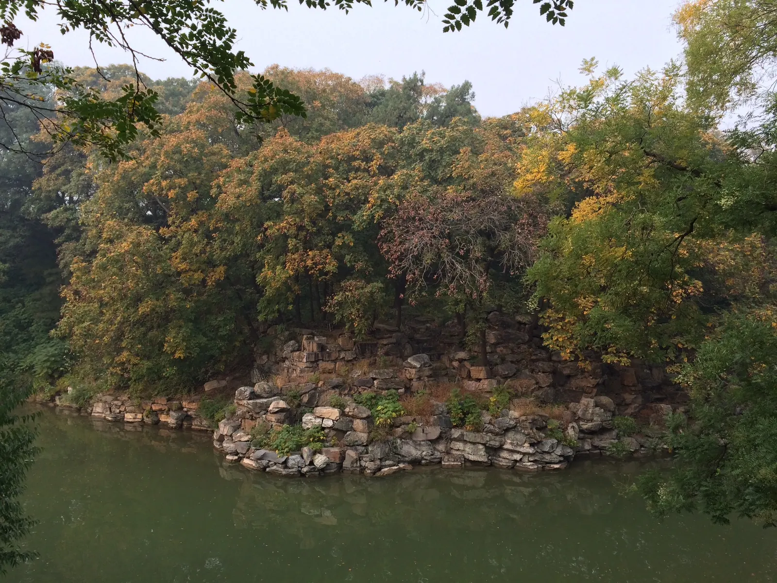 Bomen in herfstkleuren aan het water, met een oever van natuursteen in China