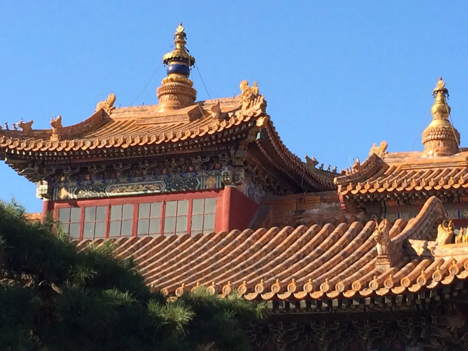 Sierlijk oranje tempeldak met gouden torentjes tegen een strakblauwe lucht in China